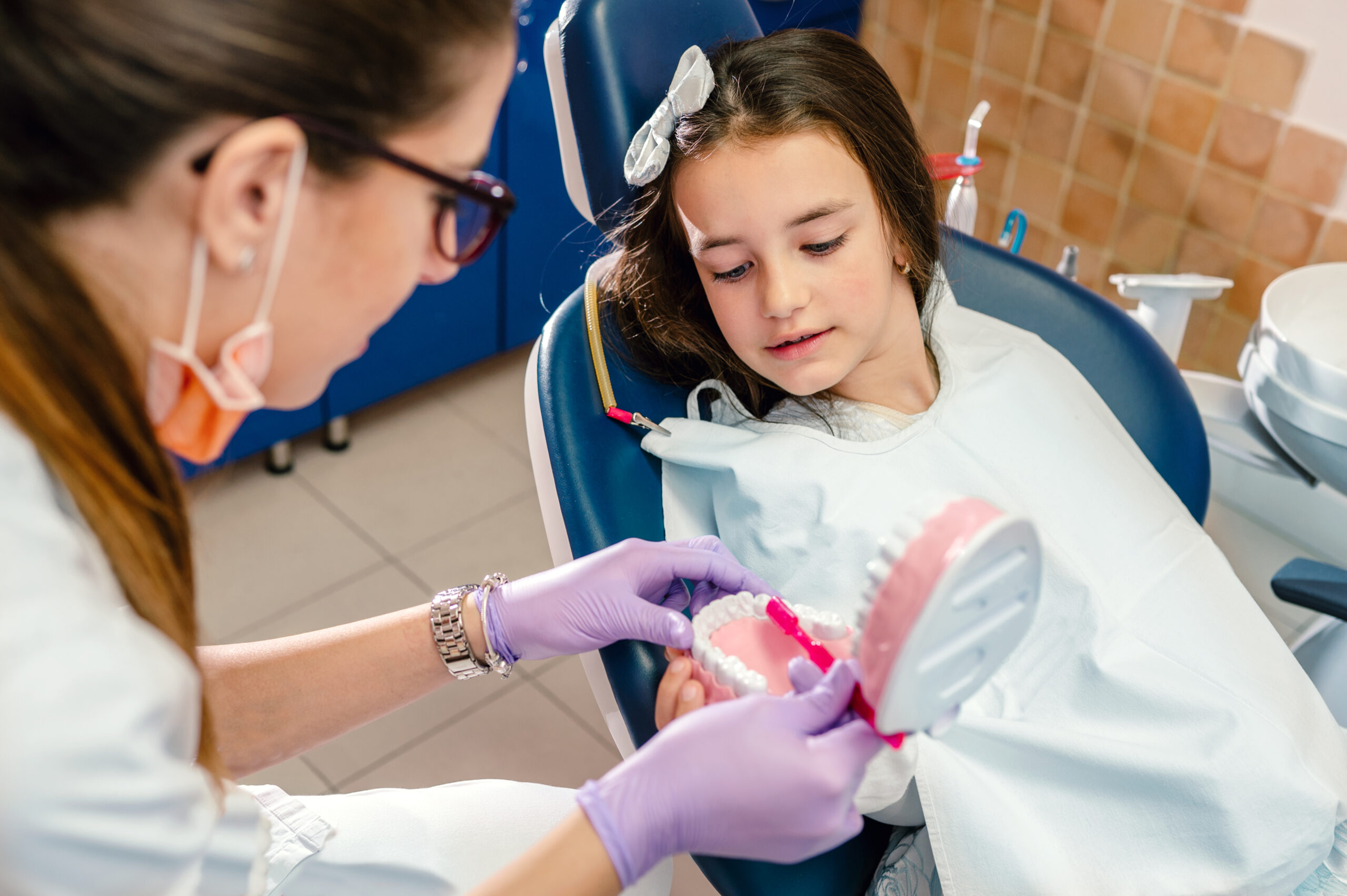 Dentist explaining how to brush teeth correctly to a patient after treatments sitting on a dentist's chair