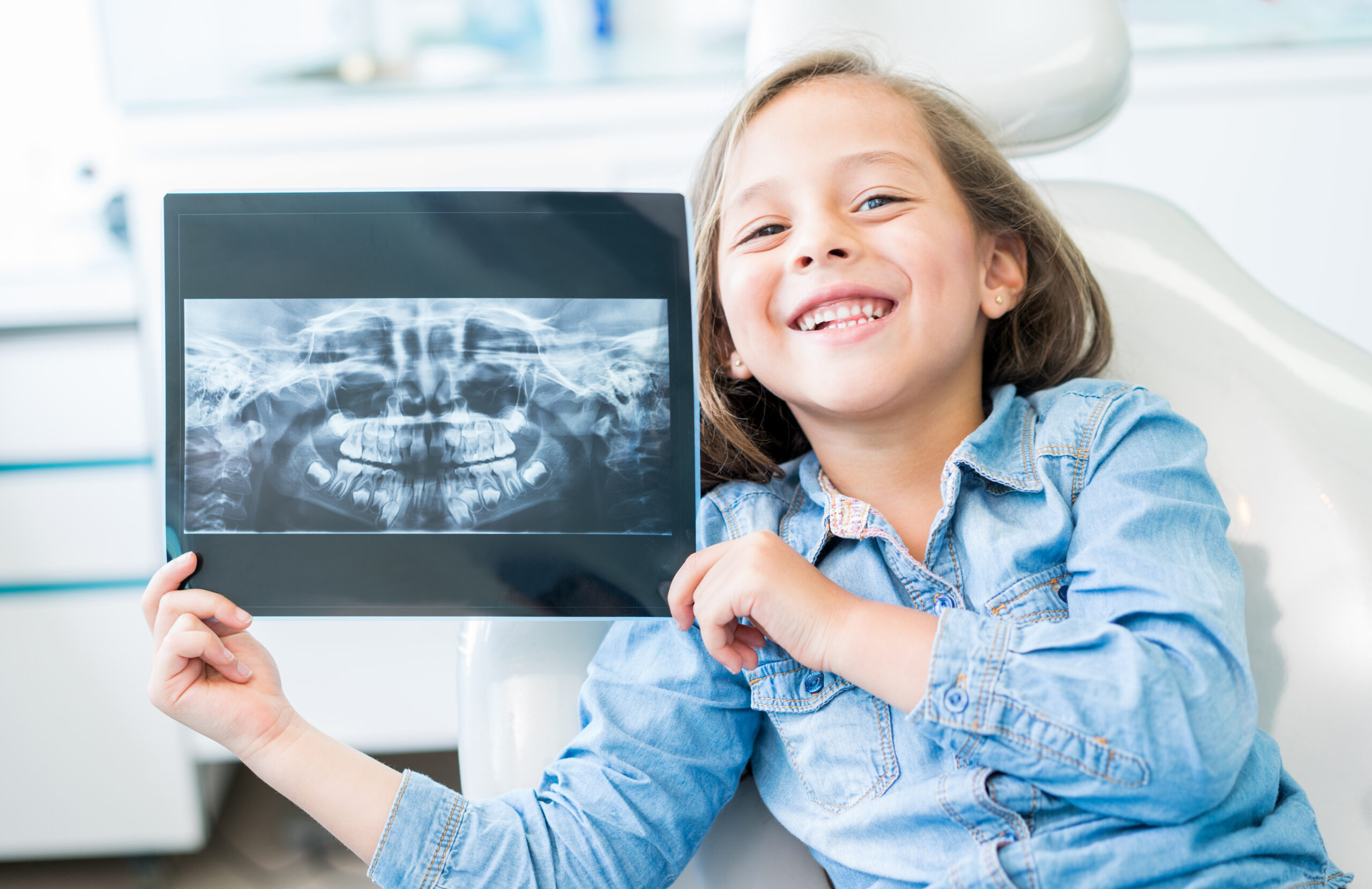 Girl at the dentist holding an x-ray Girl at the dentist holding and x-ray and looking at the camera smiling